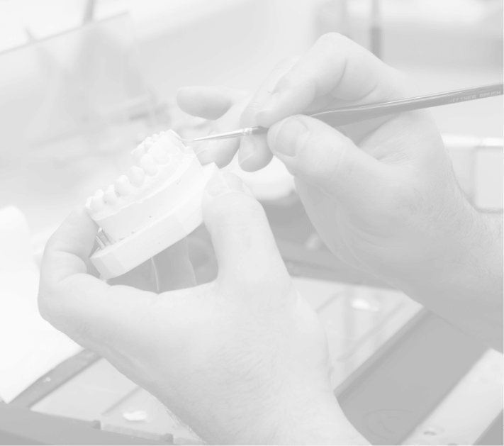 Dental technician staining crown on model